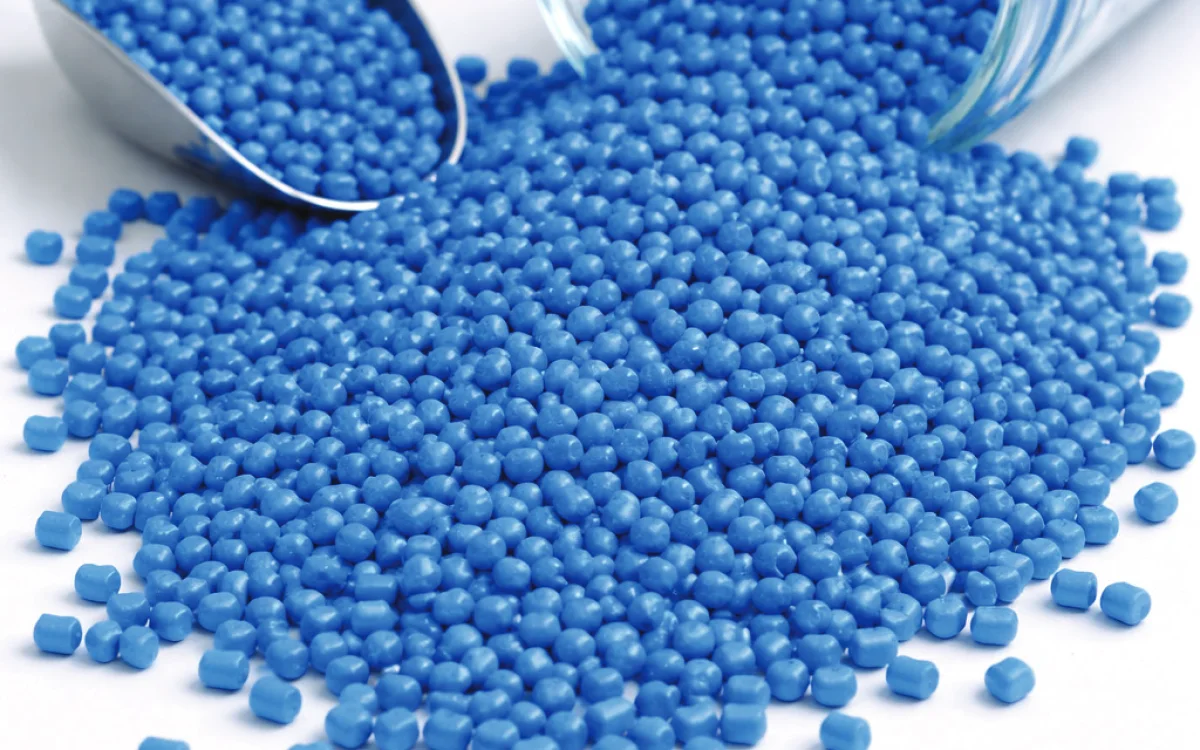 Blue polymer granules pouring from a jar